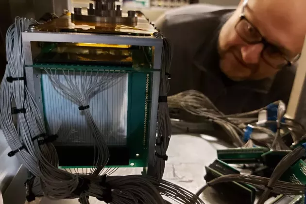 Researcher looking at a detector. Photo.