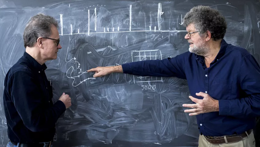 Researchers in front of a chalkboard. Photo.